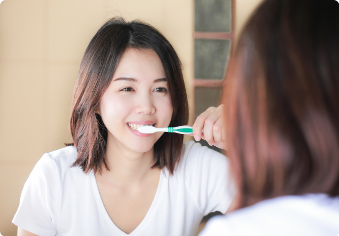 Asian girl brushing her teeth as part of good oral hygiene routine